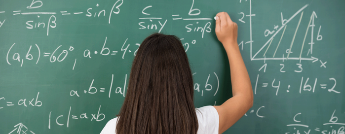 En kvinna står framför en stor grön griffeltavla med en komplicerad matematisk uträkning